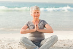 Senior woman practicing yoga on the beach